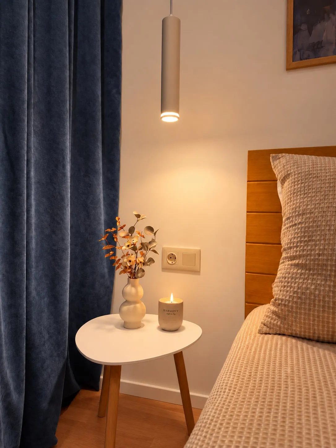 The bedside table with a candle and dried flowers under the pendant light