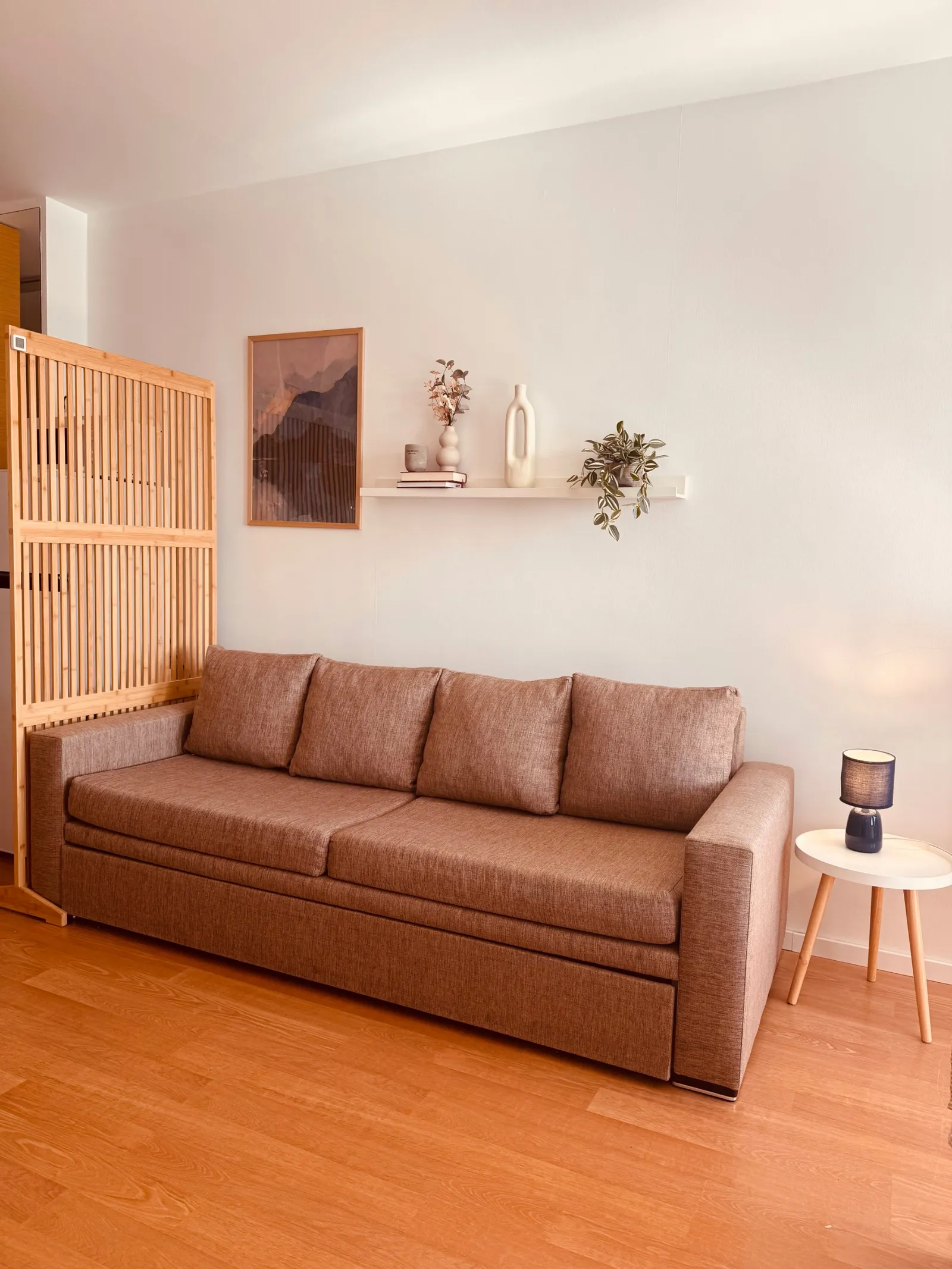 The sofa bed in the living corner, beside the wooden slatted screen